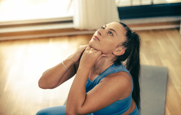 Young woman exercising at home in the morning. She is doing stretching workout.